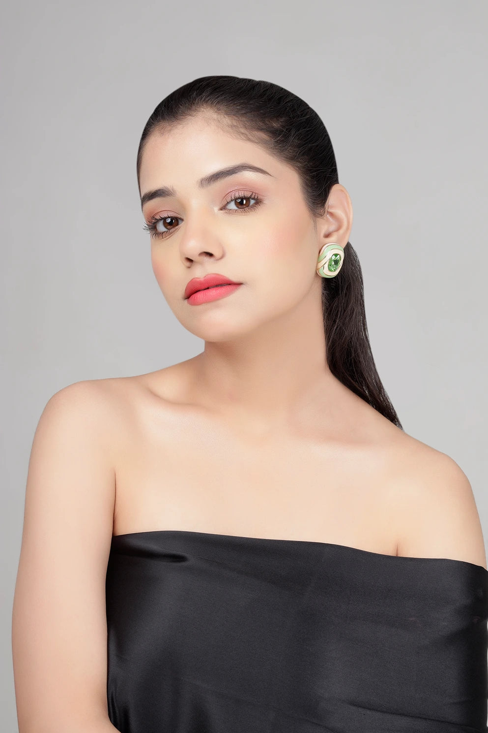 Front view of model wearing green crystal verde swirl stud earrings