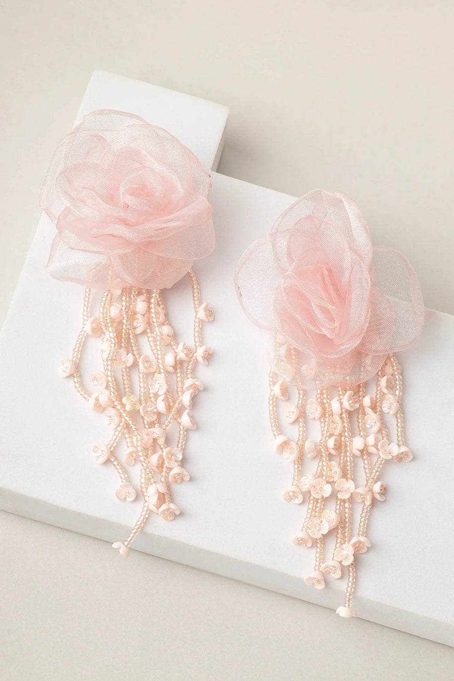 Styled shot of blush cascade pink floral pearl earrings on white blocks