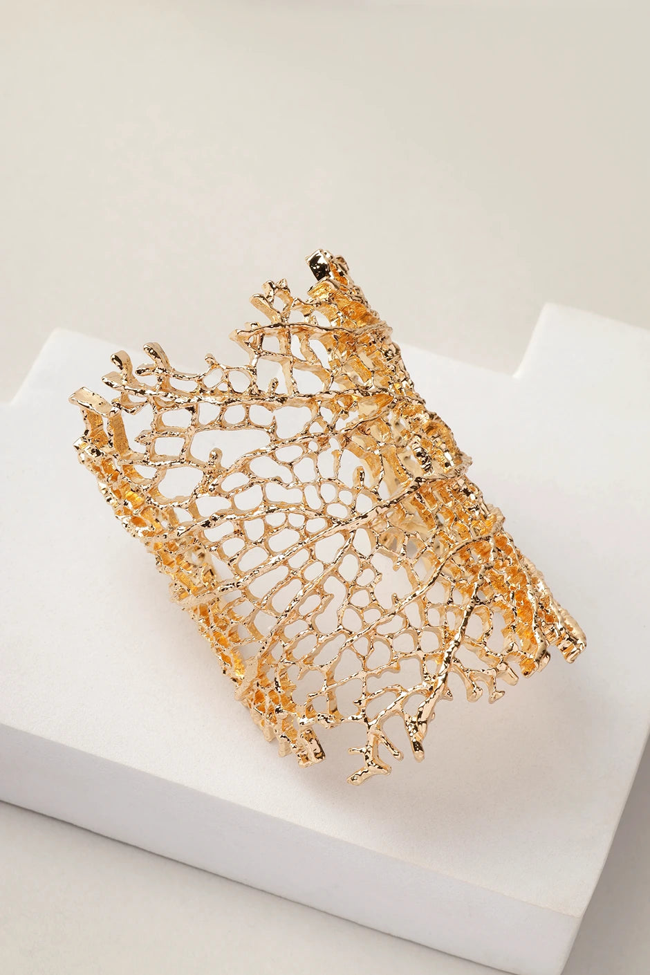 Coral Reef gold cuff bracelet displayed on white surface